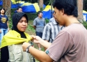 Penyematan syal dan rompi kepada peserta Kemah Pemuda Tani SPI oleh Ketua Panitia Kemah Pemud Tani SPI, Achmad Ya\'kub